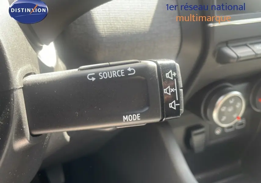 Gros plan sur la commande au volant de la Renault Clio 2025, bouton source et mode en noir mat.