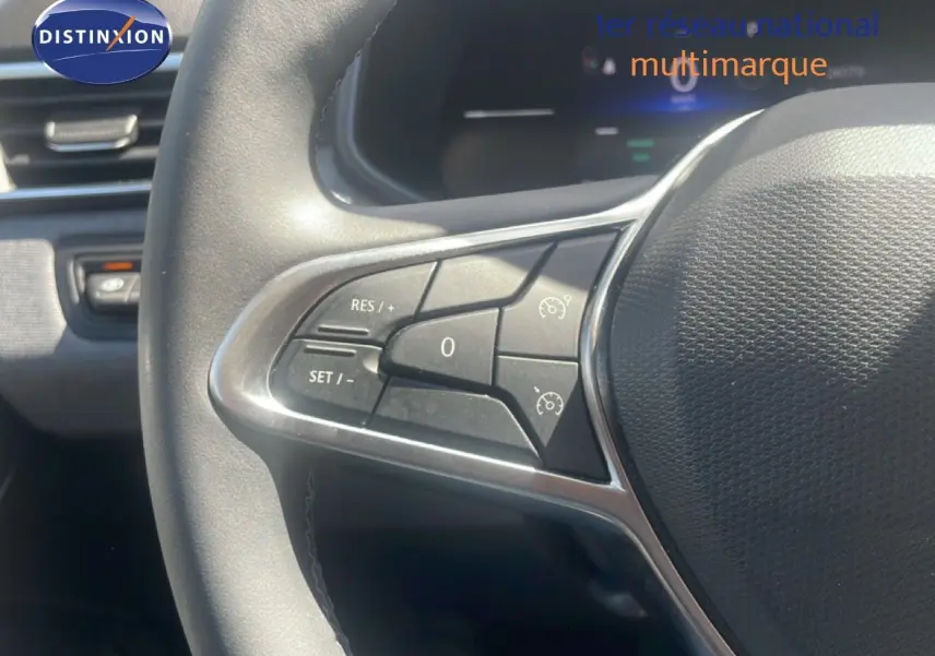 Gros plan sur les commandes au volant côté gauche de la Renault Clio blanche, version 2025, avec boutons de régulateur de vitesse.