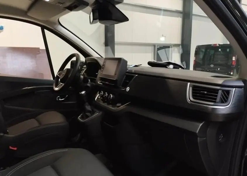 Vue intérieure côté conducteur du Nissan Primastar noir, avec tableau de bord moderne et écran tactile central.