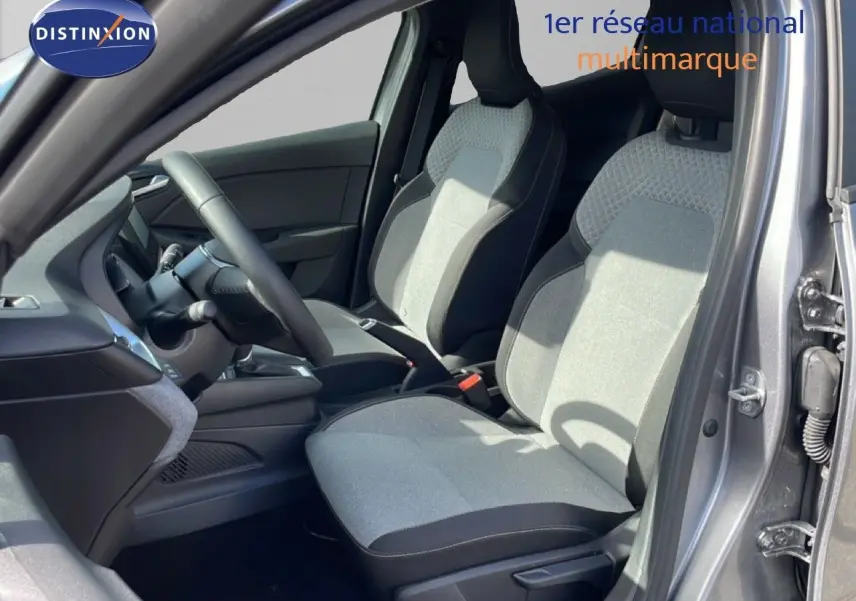 Vue intérieure côté conducteur de la Renault Clio 2025 gris schiste métal, montrant les sièges tissu bicolore et le volant cuir multifonction.