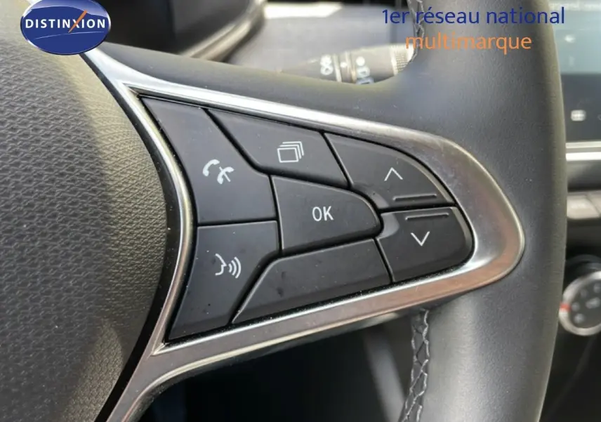 Gros plan sur les commandes multifonctions du volant en cuir noir de la Renault Clio gris schiste 2025, version Evolution.