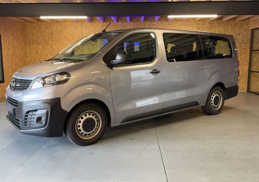 Vue 3/4 avant droit d'un Opel Vivaro Combi gris 2022 avec jantes acier et pare-chocs noirs dans un garage.