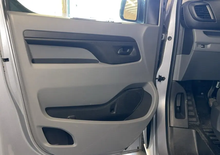 Intérieur côté gauche de la porte avant grise d'un Opel Vivaro Combi 2022, avec panneau de porte en plastique gris et noir.