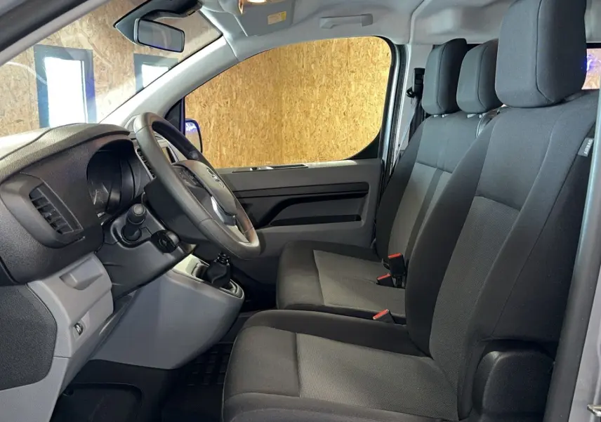 Vue intérieure côté conducteur de l'Opel Vivaro Combi gris 2022, montrant les sièges tissu et le volant multifonction.