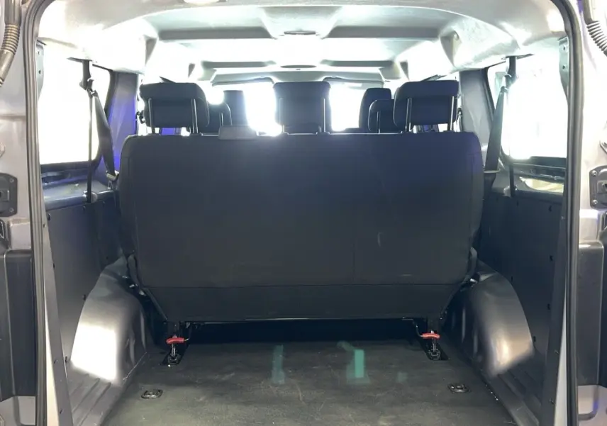 Vue arrière de l'habitacle d'un Opel Vivaro Combi gris 2022, montrant la banquette arrière en tissu noir.