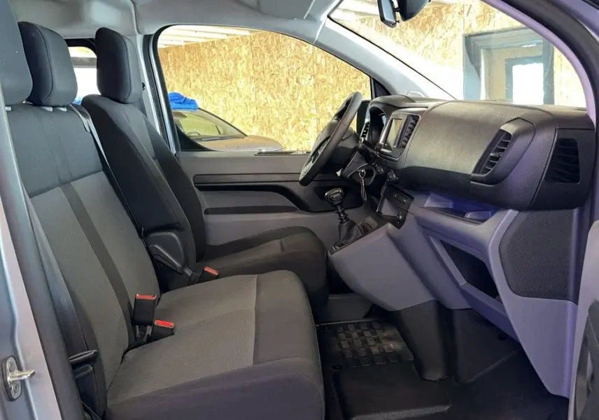 Intérieur côté gauche de l'Opel Vivaro Combi gris 2022, montrant les sièges tissu et le tableau de bord avec boîte manuelle.