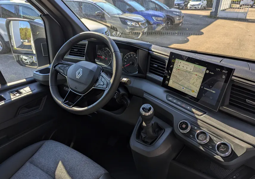 Vue intérieure côté conducteur du Renault Master 2025 avec volant multifonction, écran tactile et levier de vitesse manuel.