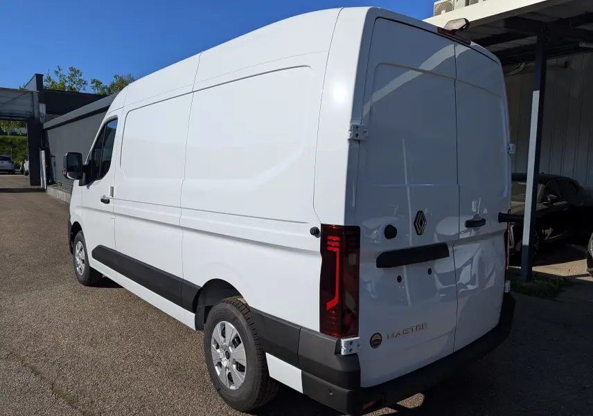Vue 3/4 arrière droite d’un Renault Master blanc 2025 avec feux arrière LED et porte arrière pleine.