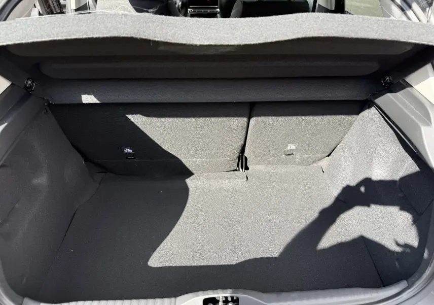 Coffre ouvert de la Citroën C3 gris platinium 2024, vue intérieure montrant l'espace de chargement et les dossiers arrière rabattus.