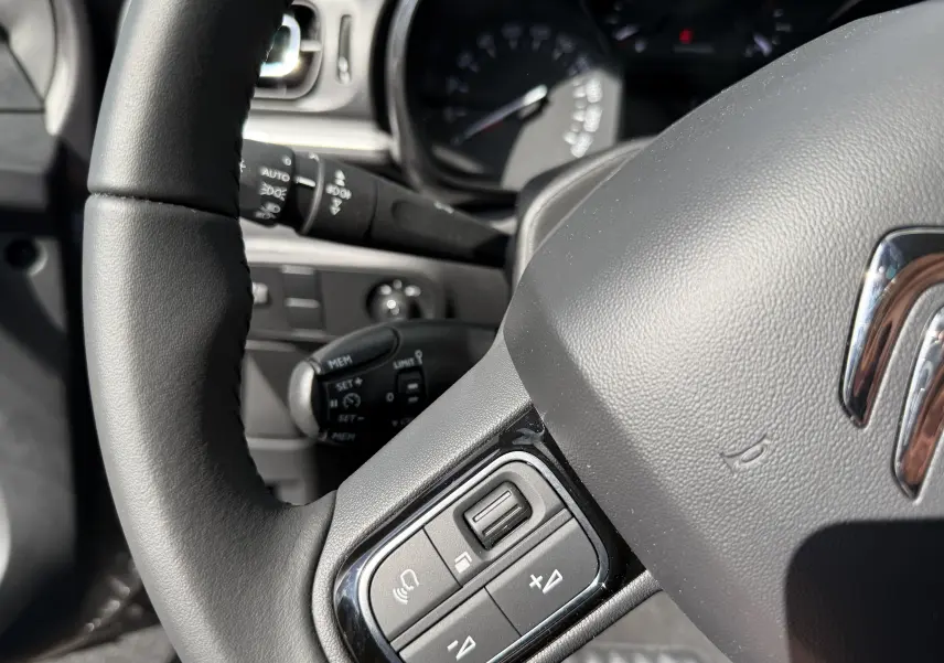 Gros plan sur le volant noir de la Citroën C3 2024 avec commandes audio intégrées, intérieur en lumière naturelle.