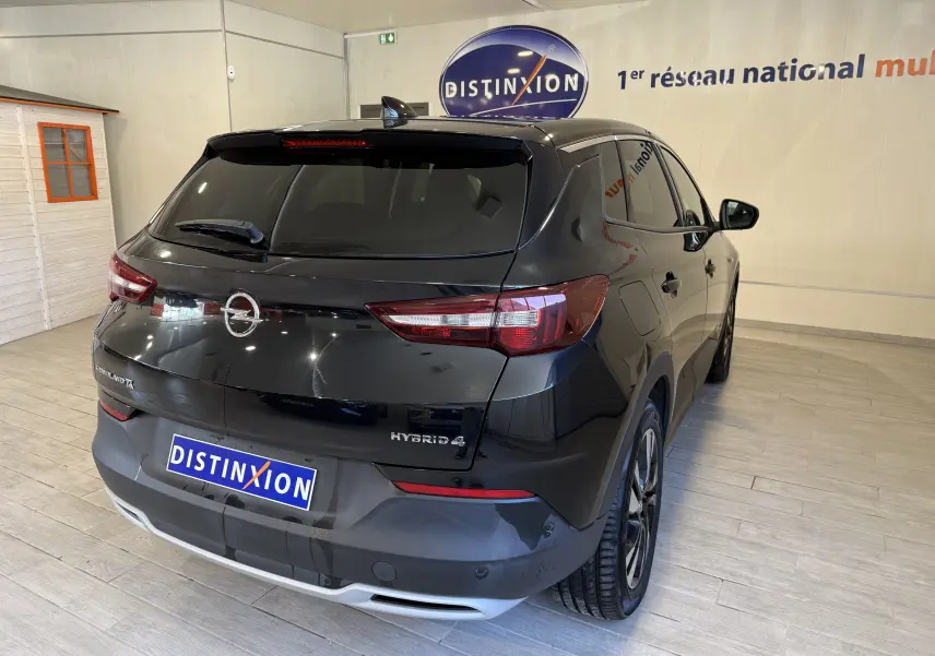 Vue 3/4 arrière droite d'un Opel Grandland X noir métal hybride rechargeable dans un showroom lumineux.