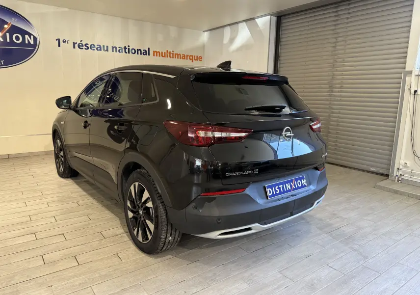 Vue 3/4 arrière droite d'un Opel Grandland X noir métal avec jantes alliage et feux arrière LED en intérieur showroom.