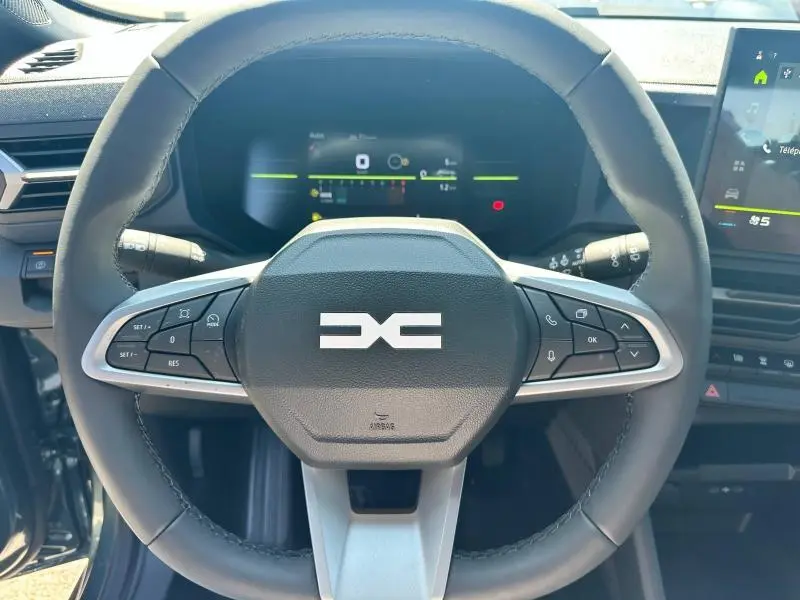 Vue rapprochée du volant multifonction du Dacia Duster 2025 avec tableau de bord numérique et écran tactile latéral.