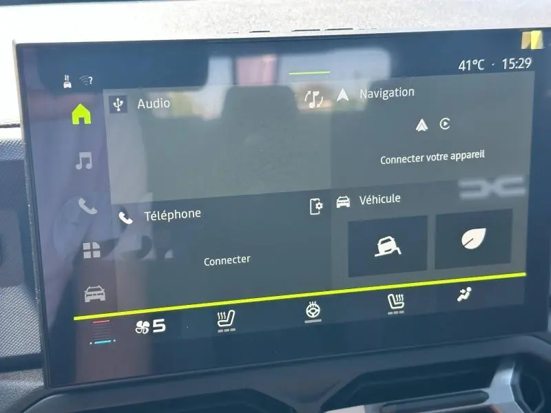 Écran tactile central du tableau de bord du Dacia Duster blanc, affichant les menus audio et navigation.
