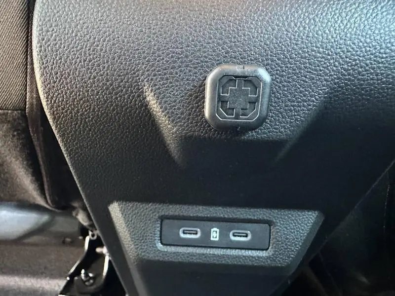 Gros plan sur la console arrière du Dacia Duster blanc 2025 montrant deux ports USB-C et une prise 12V.