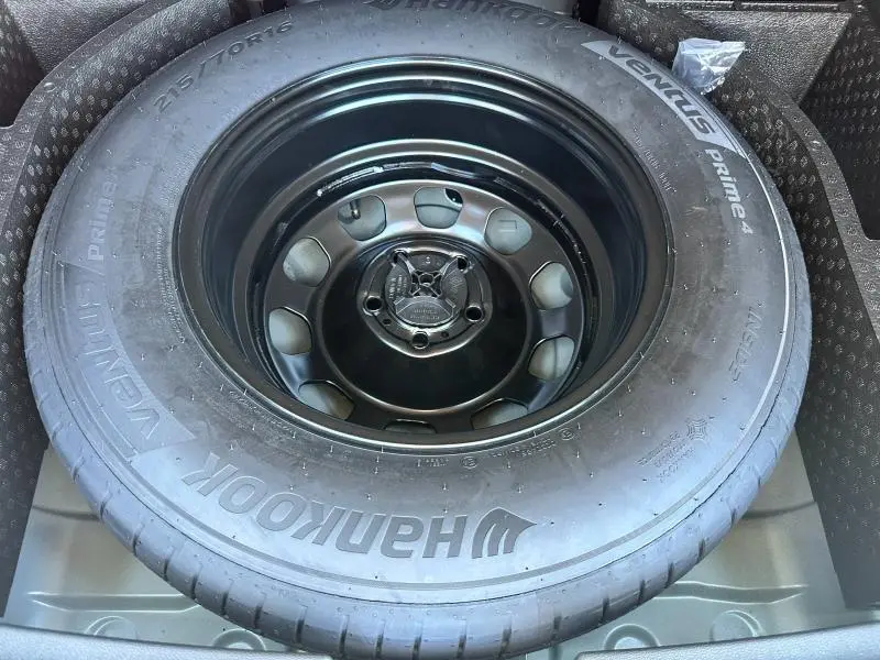 Gros plan sur la roue de secours noire du Dacia Duster 2025, entourée de son logement dans le coffre.