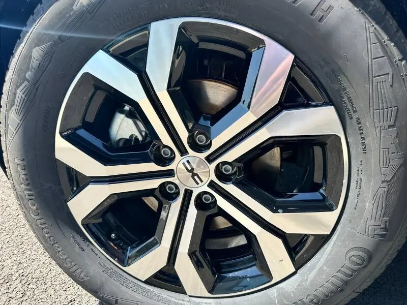 Gros plan sur la jante alu bicolore noir et argent du Dacia Duster blanc 2025, mettant en valeur son design moderne.