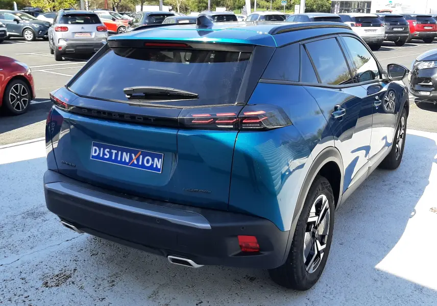 Vue 3/4 arrière droite d’un Peugeot 2008 Hybrid 145 Allure bleu obsession avec feux arrière LED et toit noir.
