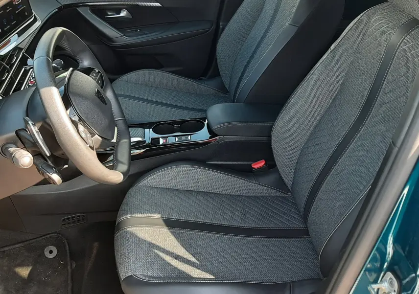 Vue intérieure côté conducteur du Peugeot 2008 Hybrid 145 Allure avec sièges gris et portière bleu obsession ouverte.