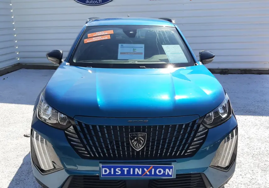 Vue frontale d'un Peugeot 2008 Hybrid 145 Allure bleu obsession, avec calandre noire et plaques Distinxion visibles.