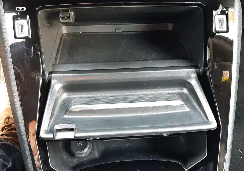 Gros plan sur la console centrale noire du Peugeot 2008 Hybrid 145 Allure, montrant le compartiment ouvert et prises USB.