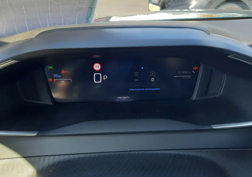 Tableau de bord numérique du Peugeot 2008 Hybrid 145, affichant la vitesse à l'arrêt et l'autonomie restante.