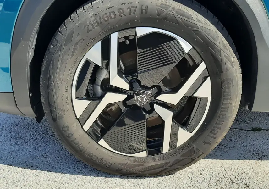 Gros plan sur la roue avant droite d’un Peugeot 2008 Bleu Obsession, jante alliage bicolore au design moderne.