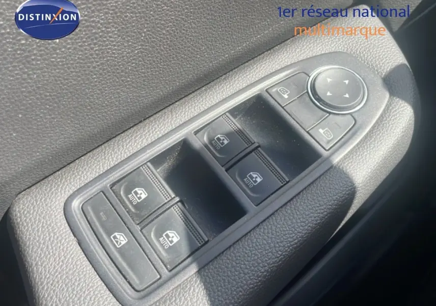 Gros plan sur les commandes de lève-vitres et rétroviseurs côté conducteur d'une Renault Clio blanche 2025.