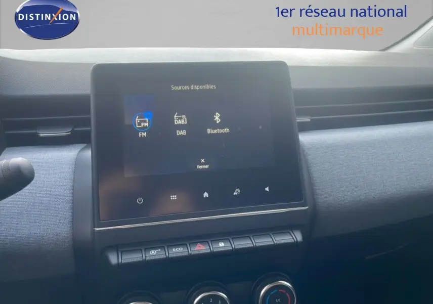 Écran tactile central de la Renault Clio 2025 blanc, affichant les options FM, DAB et Bluetooth, vue intérieure frontale.