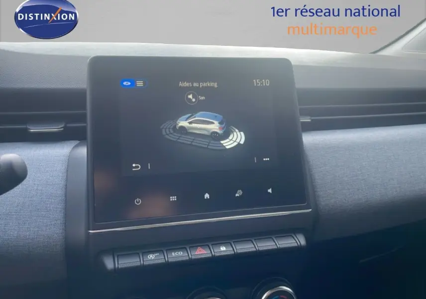 Écran tactile central affichant l'aide au parking dans l'habitacle d'une Renault Clio blanche, vue de face.