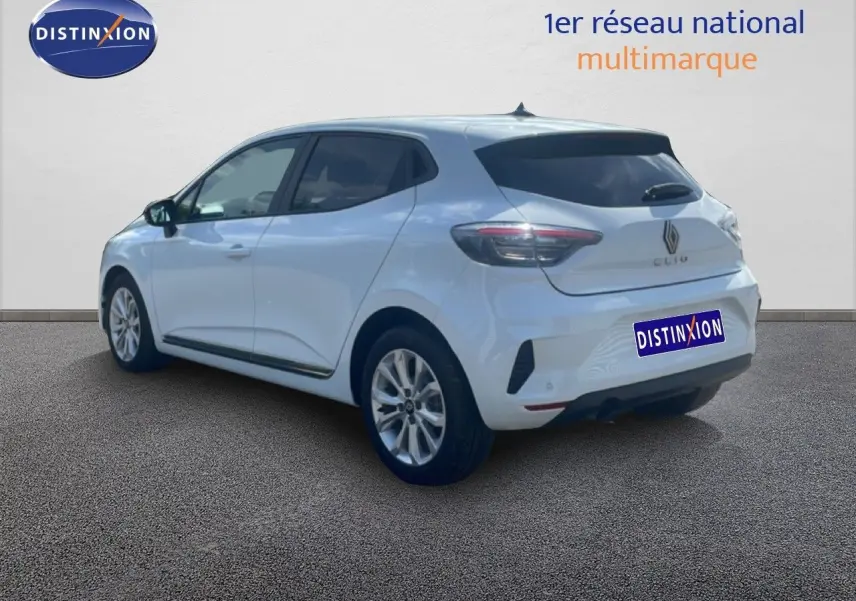 Renault Clio blanche vue 3/4 arrière droit, avec jantes alliage et vitres teintées, sur fond neutre intérieur.