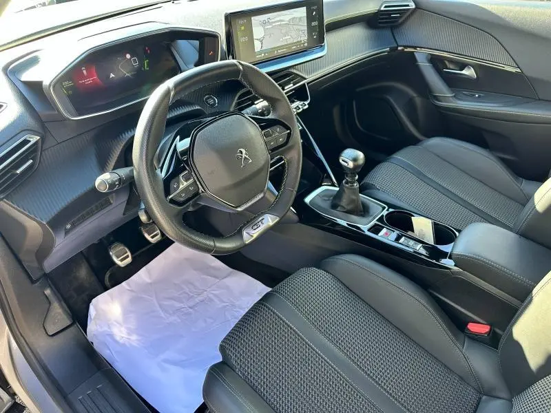 Vue intérieure côté conducteur du Peugeot 2008 gris Artense, volant cuir multifonction et levier de vitesse manuel visibles.