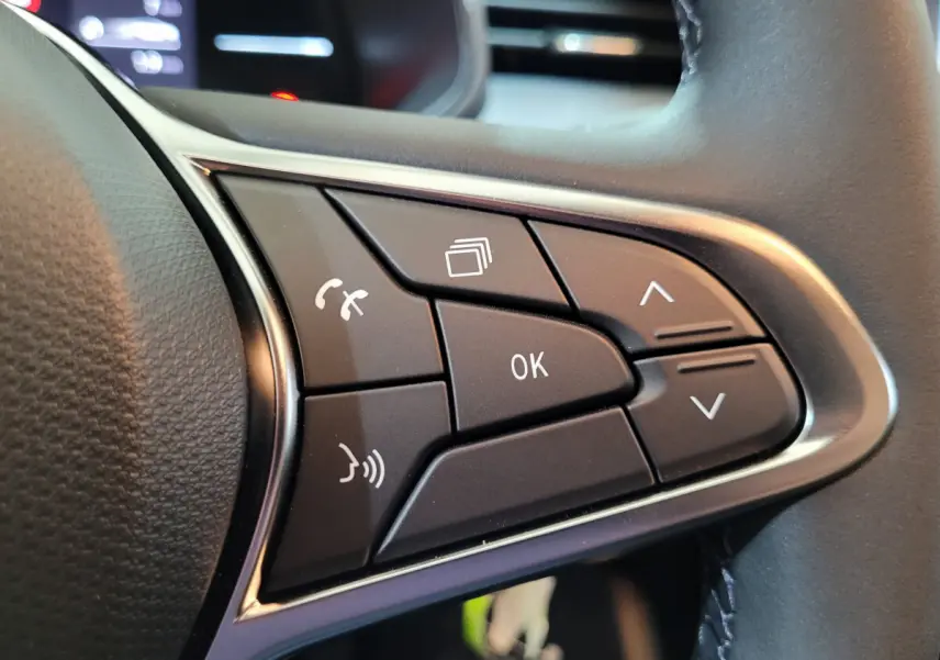 Gros plan sur les commandes multifonctions du volant en cuir synthétique d’une Renault Clio gris foncé, version 2025.