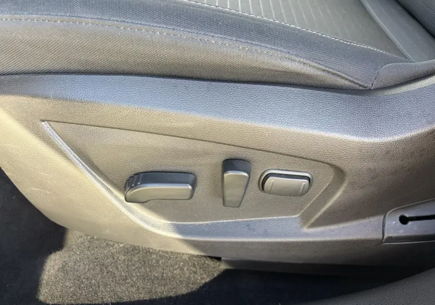 Détail des commandes de réglage électrique du siège conducteur sur Renault Arkana blanc Glacier, intérieur noir.