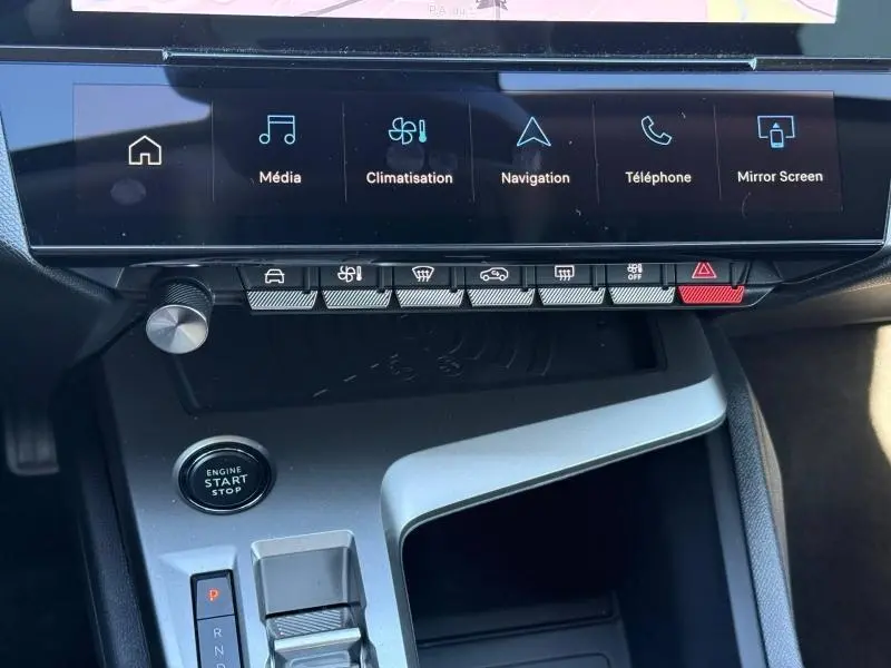Vue intérieure du tableau de bord de la Peugeot 308 hybride 2025, avec écran tactile et commandes tactiles grises.