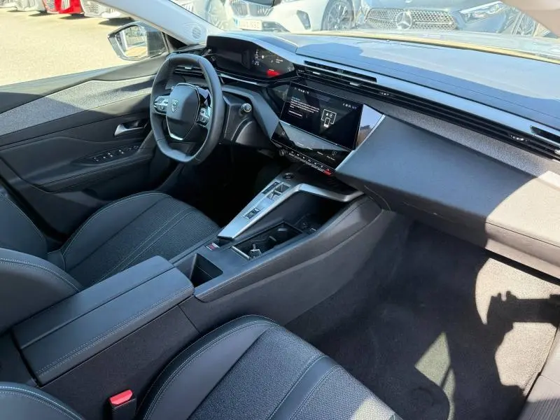 Vue intérieure côté conducteur de la Peugeot 308 1.2 Hybrid 145ch Allure 2025, avec tableau de bord numérique et écran tactile central.
