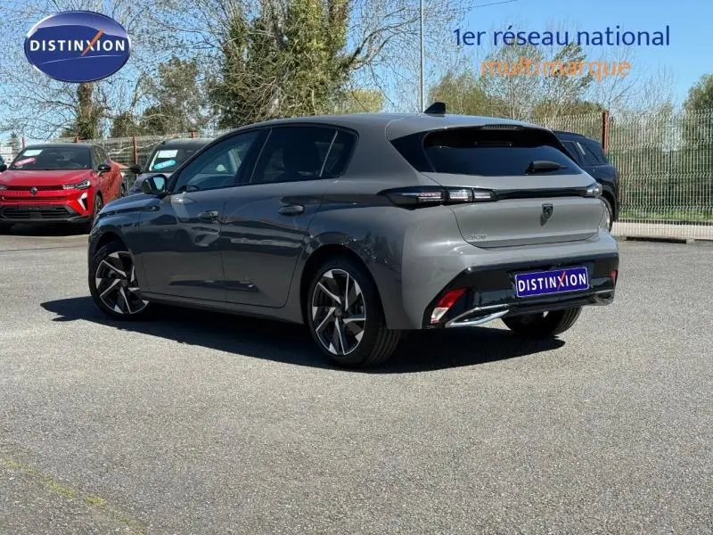 Peugeot 308 gris vue 3/4 arrière droit, version hybride 2025 avec jantes alliage et feux arrière LED fins.