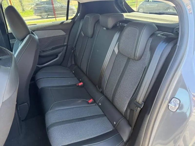 Vue intérieure côté droit des sièges arrière noirs de la Peugeot 308 1.2 Hybrid 145ch Allure 2025, avec ceinture de sécurité visible.