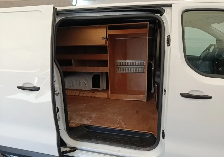 Vue latérale gauche d’un Citroën Jumpy blanc 2021 avec porte coulissante ouverte montrant l’aménagement intérieur en bois.