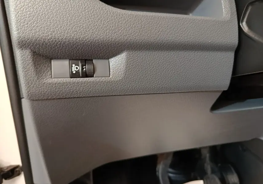 Détail intérieur du tableau de bord côté conducteur du Citroën Jumpy blanc, bouton de réglage des phares visible.