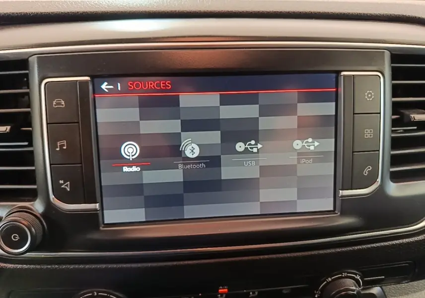 Écran tactile central du tableau de bord du Citroën Jumpy blanc, affichant les sources audio radio, Bluetooth, USB et iPod.