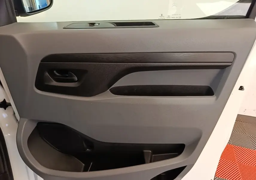 Vue rapprochée de la porte intérieure côté gauche du Citroën Jumpy XS blanc, avec poignée et rangements intégrés.