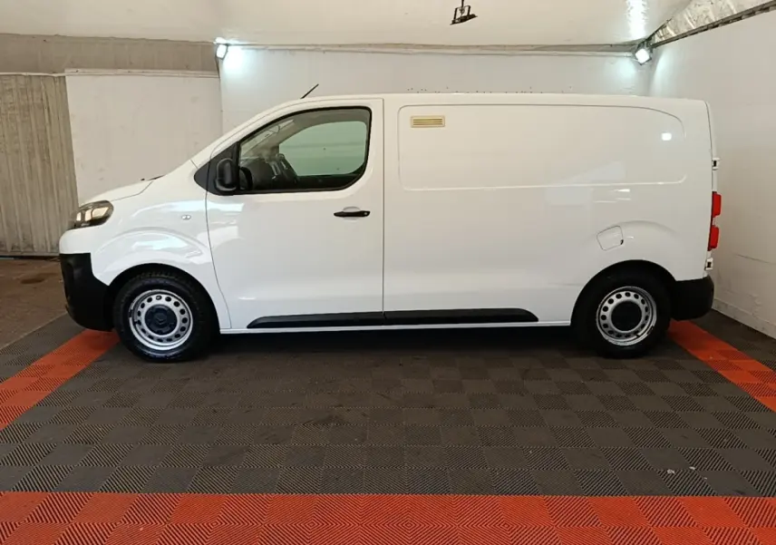 Vue de profil côté gauche d’un utilitaire Citroën Jumpy XS BlueHDi 120 blanc, roues acier et pare-chocs noirs.