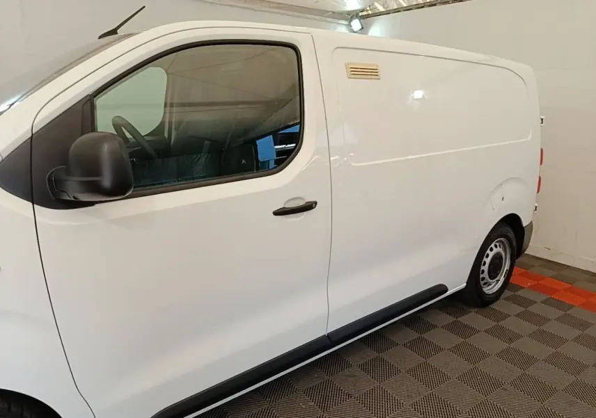Vue de profil côté gauche d’un utilitaire Citroën Jumpy blanc, avec porte latérale pleine et jantes acier.