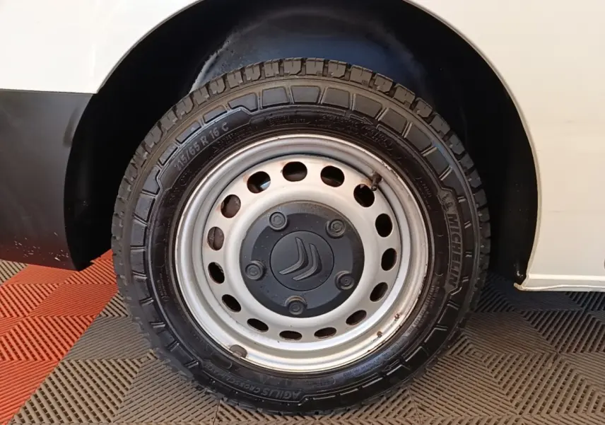 Gros plan sur la roue avant droite acier avec logo Citroën, sur fond de carrosserie blanche du Citroën Jumpy XS.