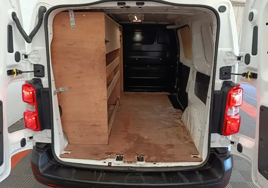 Vue arrière ouverte du Citroën Jumpy blanc montrant l’espace de chargement avec étagères en bois à gauche.