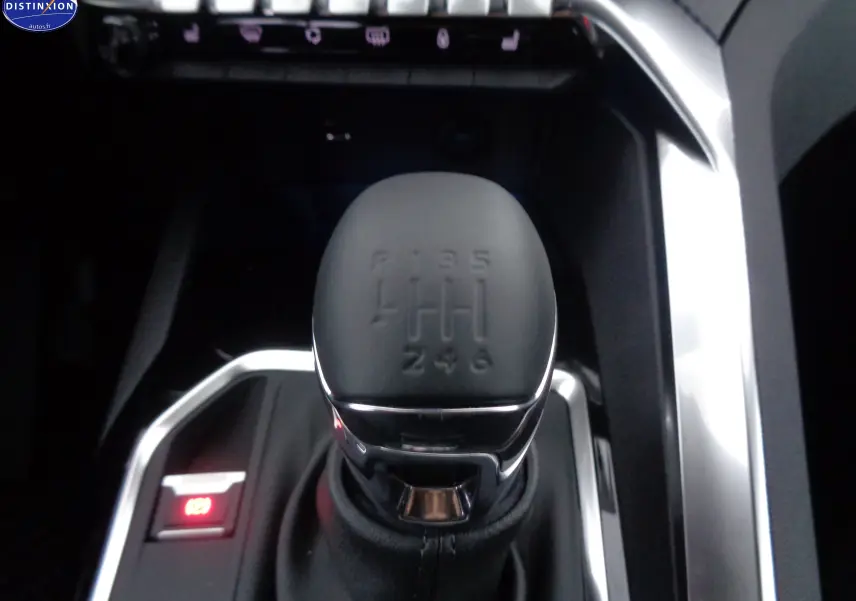 Gros plan sur le levier de vitesses manuel noir du Peugeot 3008 gris Artense, avec éclairage rouge du frein à main électronique.