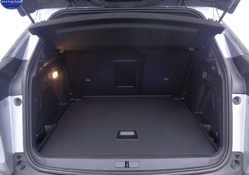 Coffre ouvert d'un Peugeot 3008 gris Artense métal, vue arrière montrant un espace de chargement spacieux et bien éclairé.