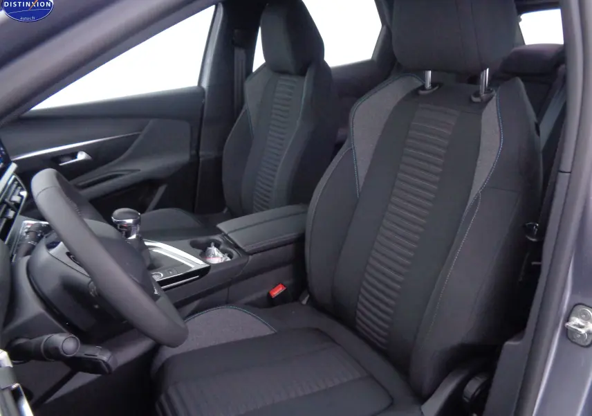 Vue intérieure côté conducteur du Peugeot 3008 2023 gris Artense Metal, sièges tissu gris et noir avec surpiqûres bleues.