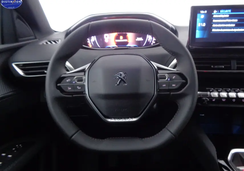 Vue rapprochée du volant Peugeot 3008 2023 avec commandes intégrées et tableau de bord numérique éclairé.